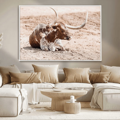 Texas Longhorn bull resting on dusty ground with warm tones, ideal for rustic western or farmhouse-themed wall decor.