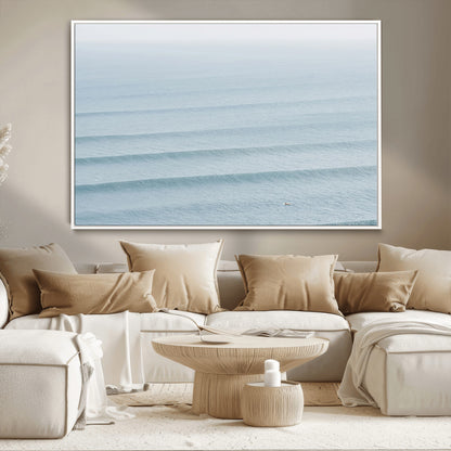Framed canvas of repeating ocean waves with a distant solo surfer, ideal for minimalist ocean or calm coastal wall decor.