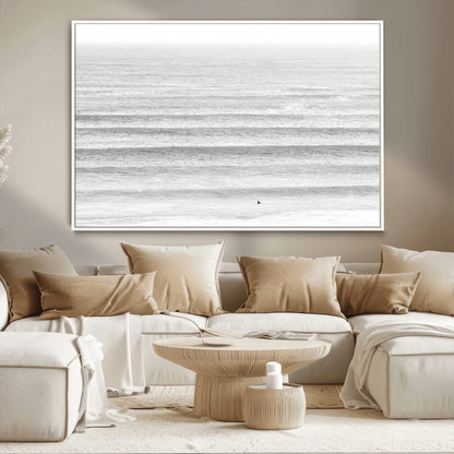 Monochrome photo of a lone surfer in calm layered waves, perfect for minimalist coastal or moody ocean-inspired wall decoration.