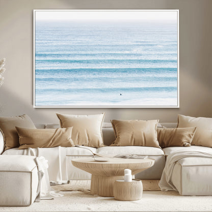 Minimalist ocean view with soft blue waves and a lone surfer, creating a serene and airy coastal aesthetic, perfect for tranquil home decor.