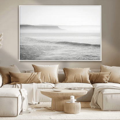 A black and white minimalist seascape featuring soft rolling waves and misty distant cliffs, creating a serene and timeless coastal atmosphere.