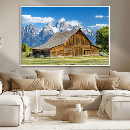 A rustic wooden barn sits in front of towering mountain peaks under a clear blue sky, perfect for farmhouse or cabin style interiors.