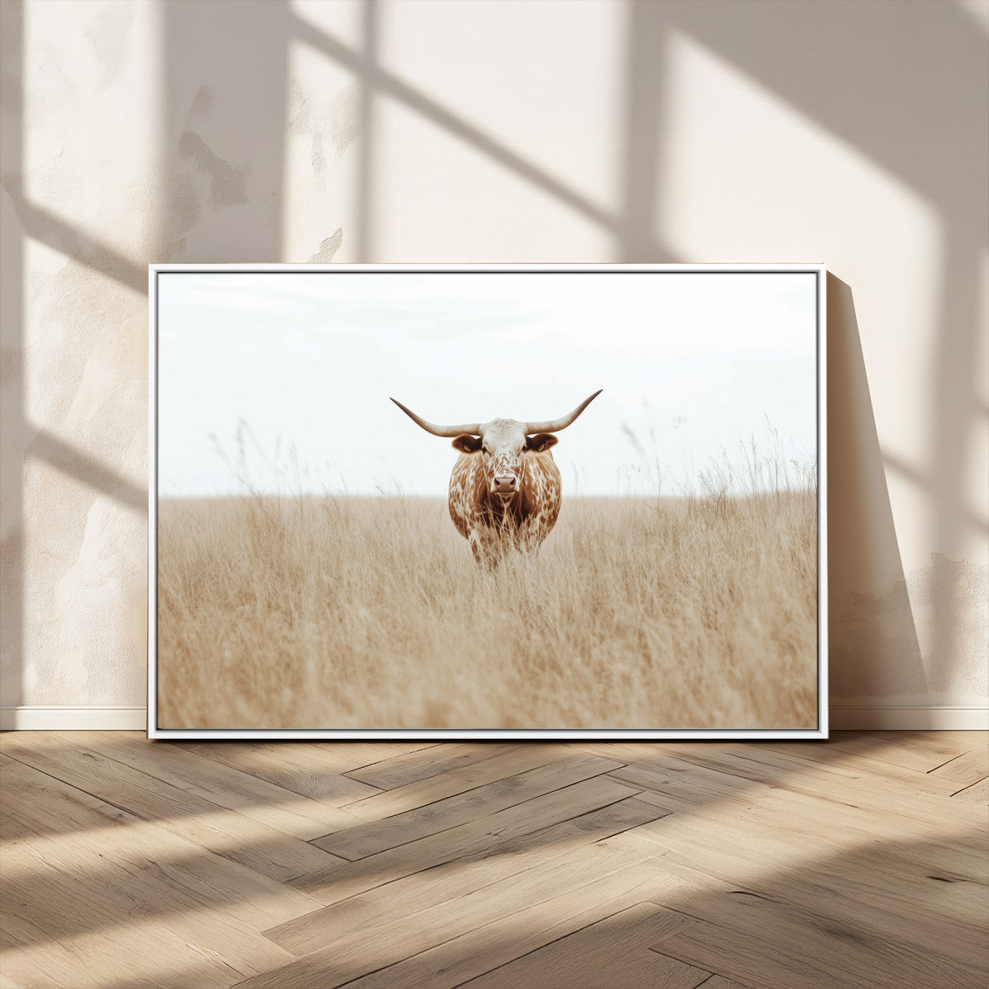 Texas Longhorn bull standing alone in dry grass with neutral tones, ideal for rustic western or cowboy-themed wall decor.