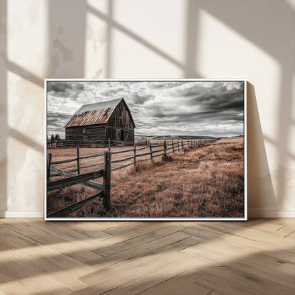 Framed canvas of a rustic barn under a moody sky with weathered fence and dark fields, ideal for farmhouse or rural-style wall decor.