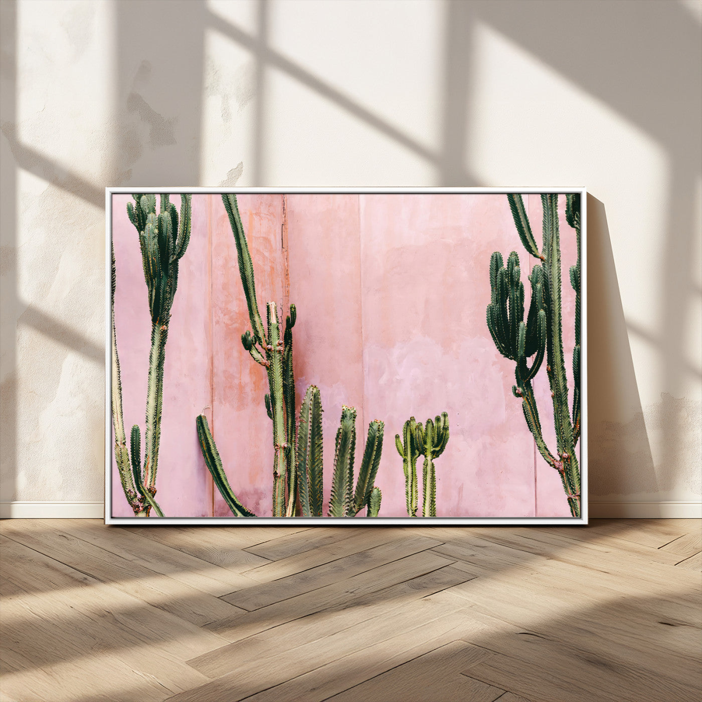 Framed canvas of tall green cacti against a soft pink wall, ideal for modern desert or colorful southwest-inspired home decor.