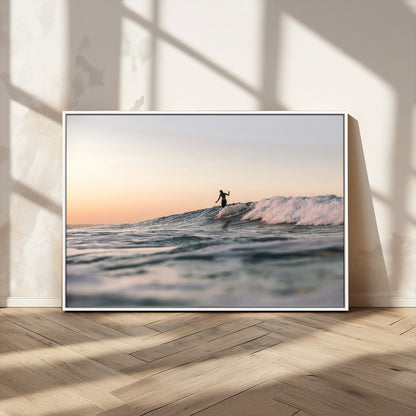 Framed canvas of a female surfer balancing on a wave at sunset, perfect for serene surf or ocean-inspired coastal decor.