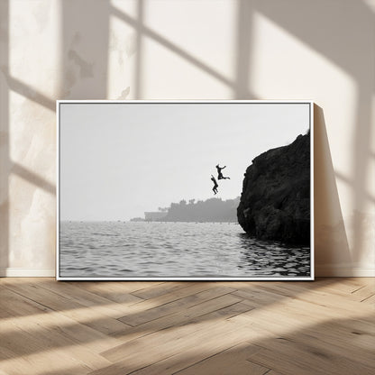 Black and white canvas of two figures cliff jumping into the sea, captured with moody tones, ideal for modern coastal or adventure-themed home decor.   2/2