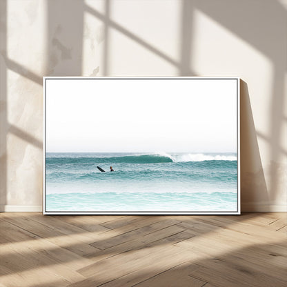 Minimalist photo of a lone surfer on calm aqua waves under bright sky, perfect for Scandinavian coastal or serene ocean-inspired home decor.