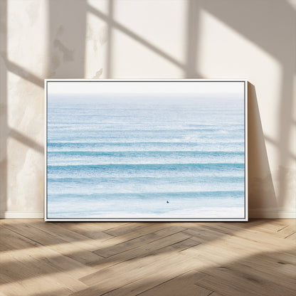 Minimalist ocean view with soft blue waves and a lone surfer, creating a serene and airy coastal aesthetic, perfect for tranquil home decor.