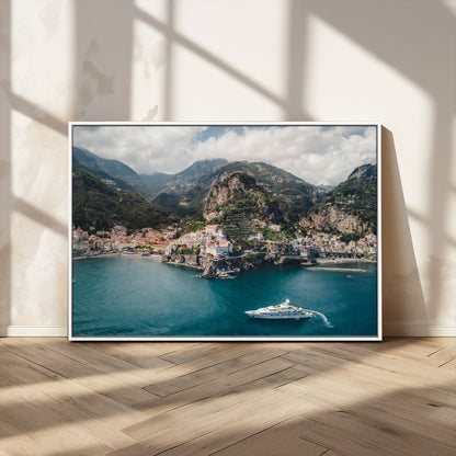Aerial view of Amalfi Coast, Italy, with colorful hillside houses, lush green mountains, and a luxury yacht sailing in turquoise waters.