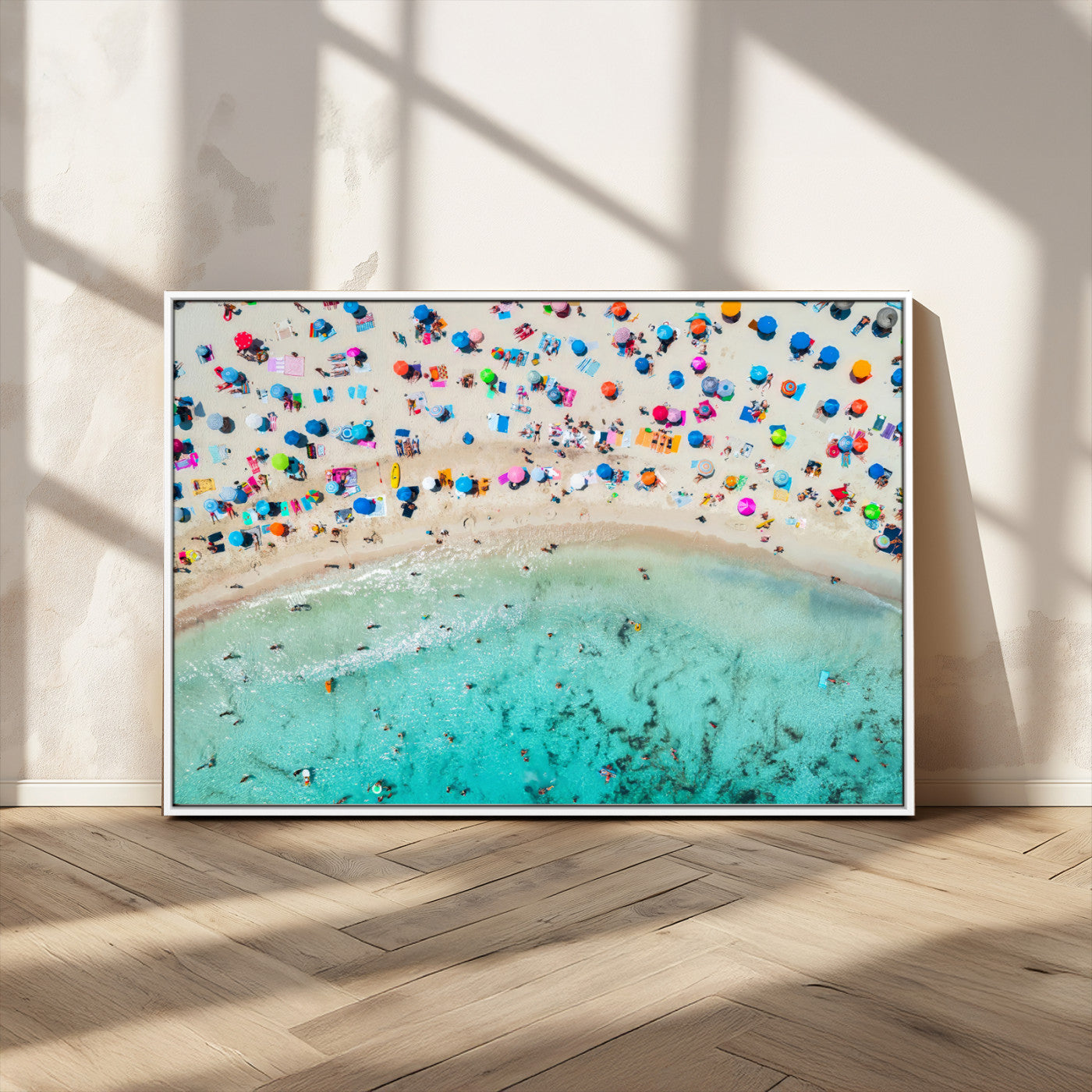 Aerial view of a vibrant beach filled with colorful umbrellas and people enjoying the turquoise ocean, capturing a lively summer vacation scene.