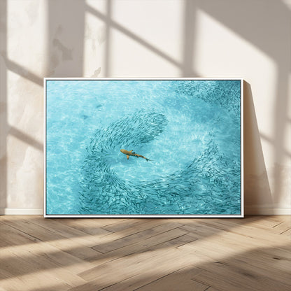 Aerial view of a shark swimming through a swirl of fish in clear turquoise waters, perfect for calm coastal or beach house decor.