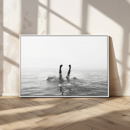 A black and white minimalist water scene capturing a playful splash as a swimmer dives upside down, creating a carefree and artistic aquatic aesthetic.
