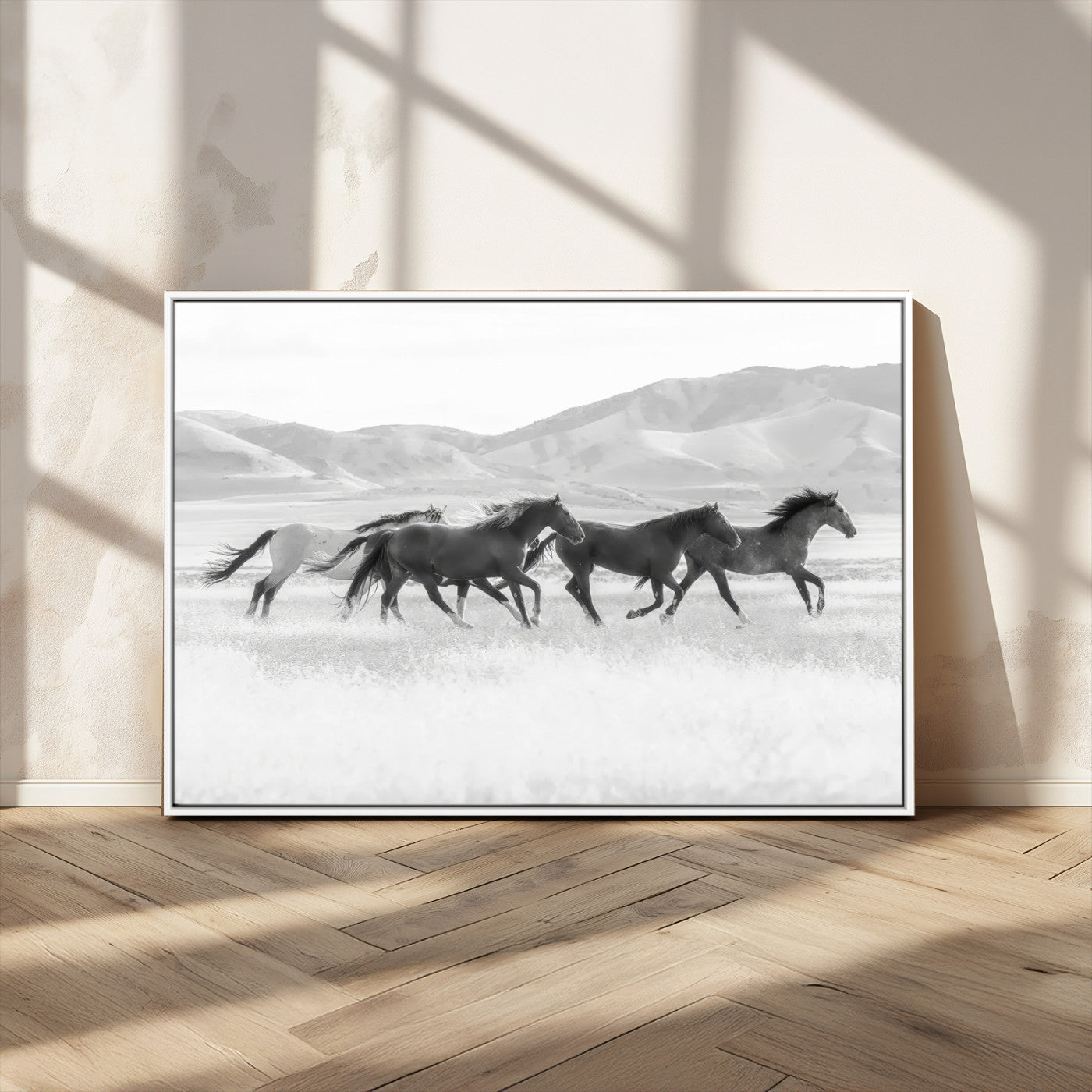 A black and white image of wild horses running freely across an open grassland, capturing the power and beauty of untamed nature in a rustic western setting.