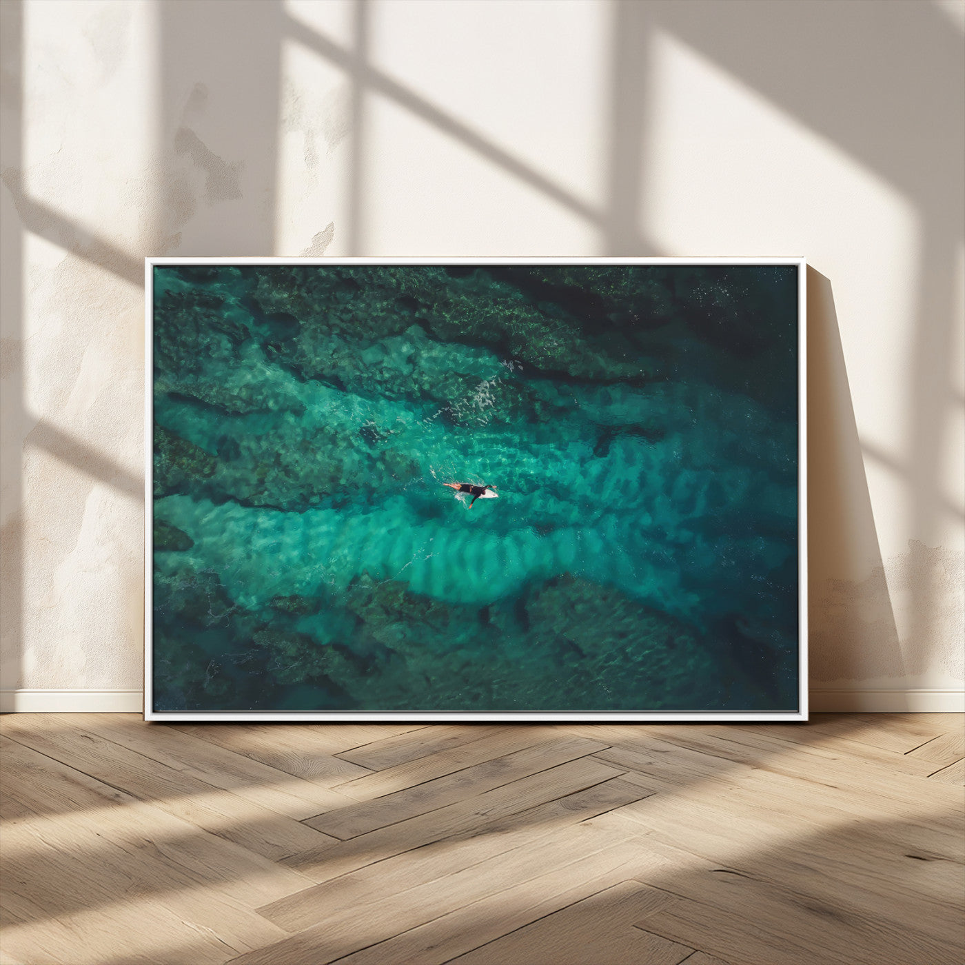 An aerial view of a solo surfer paddling through crystal-clear turquoise waters over a sunlit reef, capturing the beauty and serenity of open water surfing.