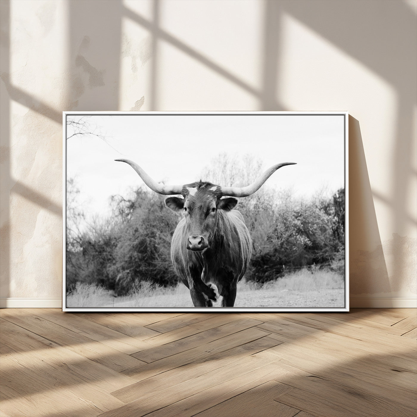 Black and white photo of a longhorn cow in a field, perfect for rustic farmhouse or western-themed interior wall decoration.