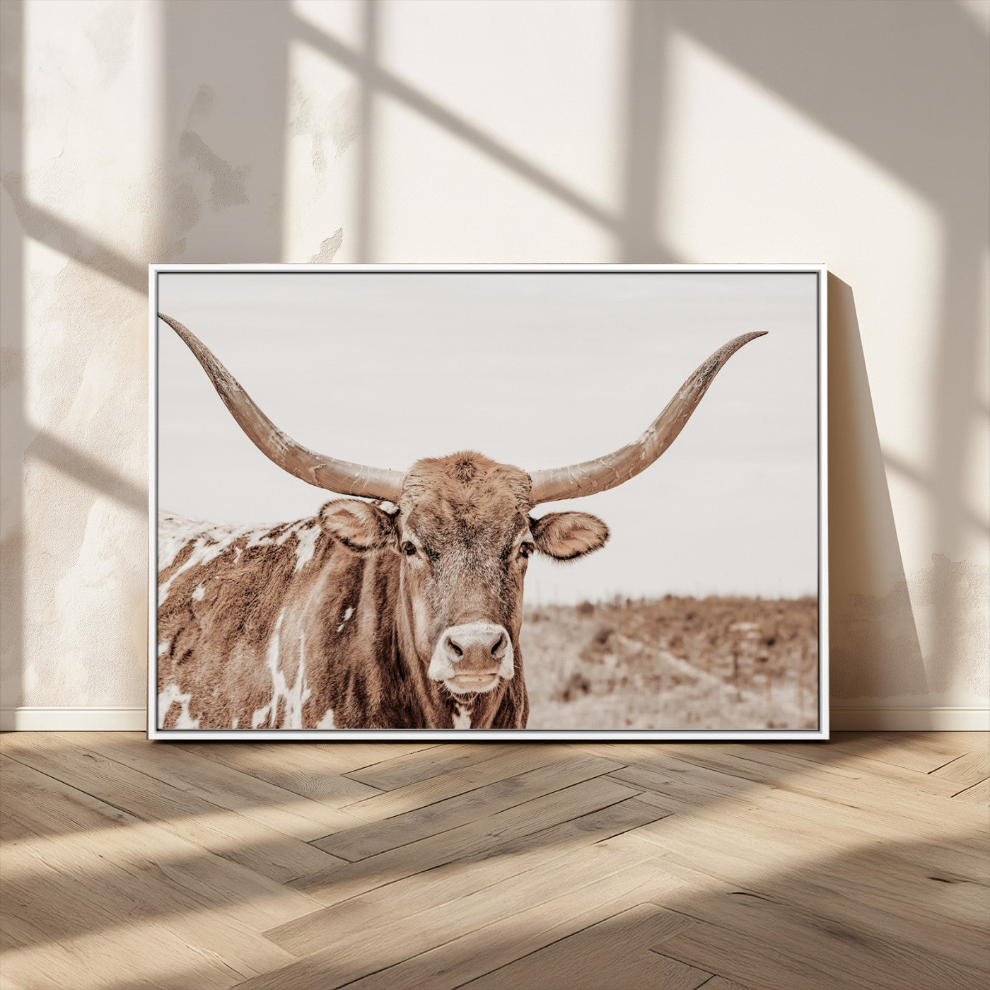 A longhorn cow in soft beige desert tones, standing calmly in open land, perfect for neutral western or rustic farmhouse interiors.