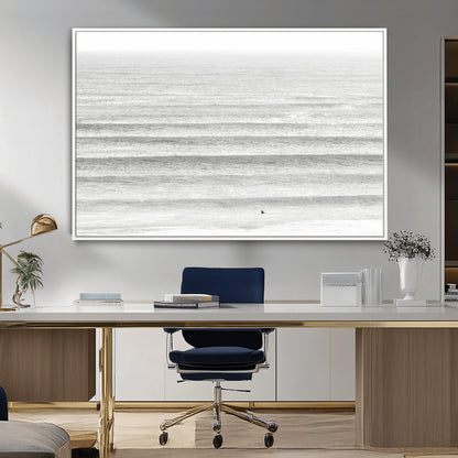 Monochrome photo of a lone surfer in calm layered waves, perfect for minimalist coastal or moody ocean-inspired wall decoration.