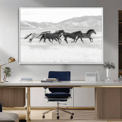 A black and white image of wild horses running freely across an open grassland, capturing the power and beauty of untamed nature in a rustic western setting.