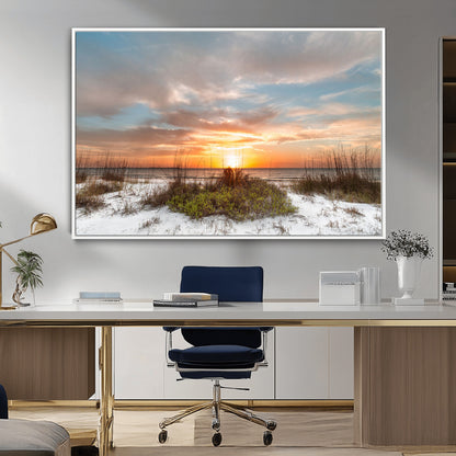 A tranquil beach scene featuring golden sunset hues over the water, with grasses in the foreground and a peaceful, serene atmosphere.