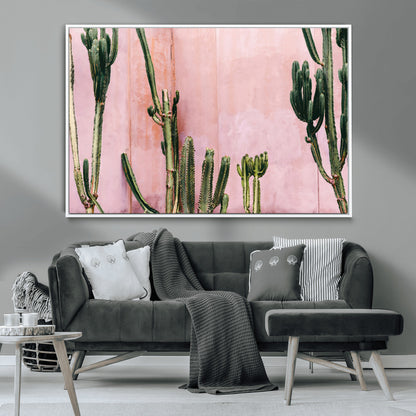 Framed canvas of tall green cacti against a soft pink wall, ideal for modern desert or colorful southwest-inspired home decor.