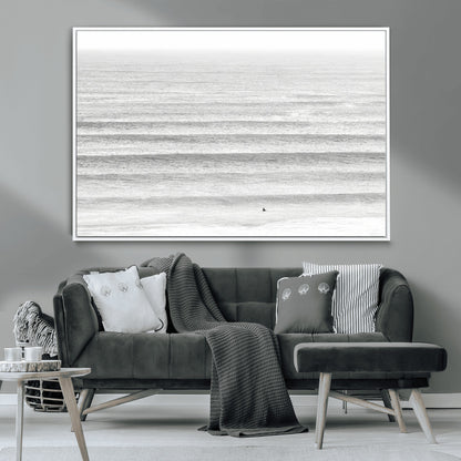 Monochrome photo of a lone surfer in calm layered waves, perfect for minimalist coastal or moody ocean-inspired wall decoration.