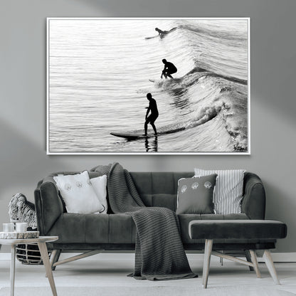 Black and white photo of surfers riding waves in a moody, high-contrast scene, ideal for modern coastal or surf-inspired home decor.