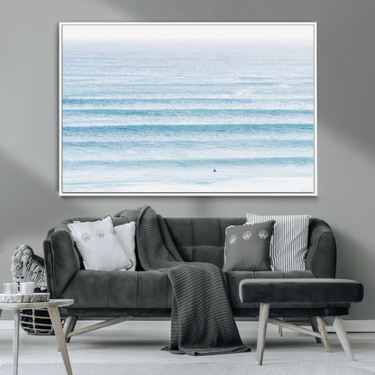Minimalist ocean view with soft blue waves and a lone surfer, creating a serene and airy coastal aesthetic, perfect for tranquil home decor.