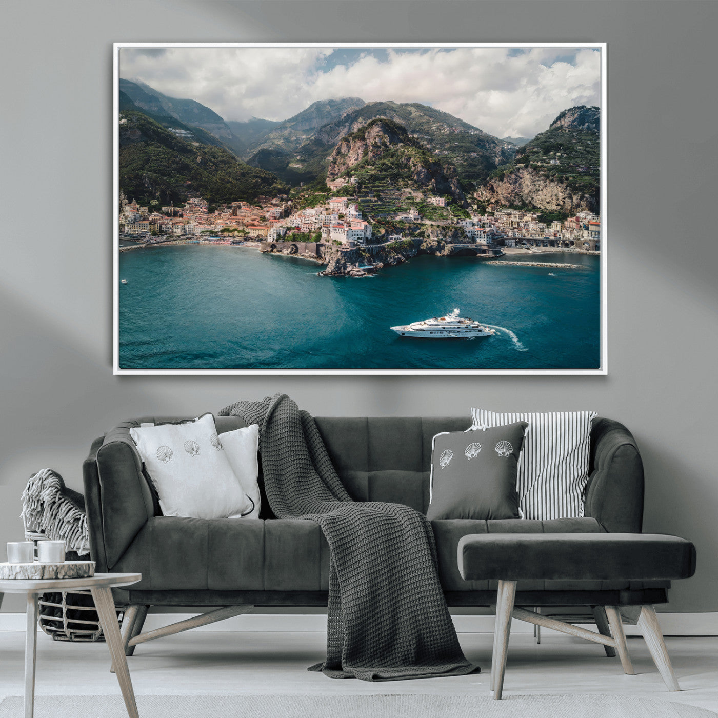 Aerial view of Amalfi Coast, Italy, with colorful hillside houses, lush green mountains, and a luxury yacht sailing in turquoise waters.