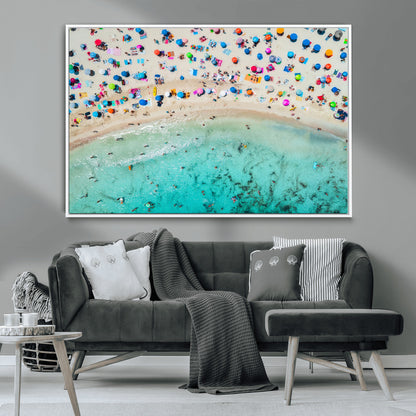 Aerial view of a vibrant beach filled with colorful umbrellas and people enjoying the turquoise ocean, capturing a lively summer vacation scene.