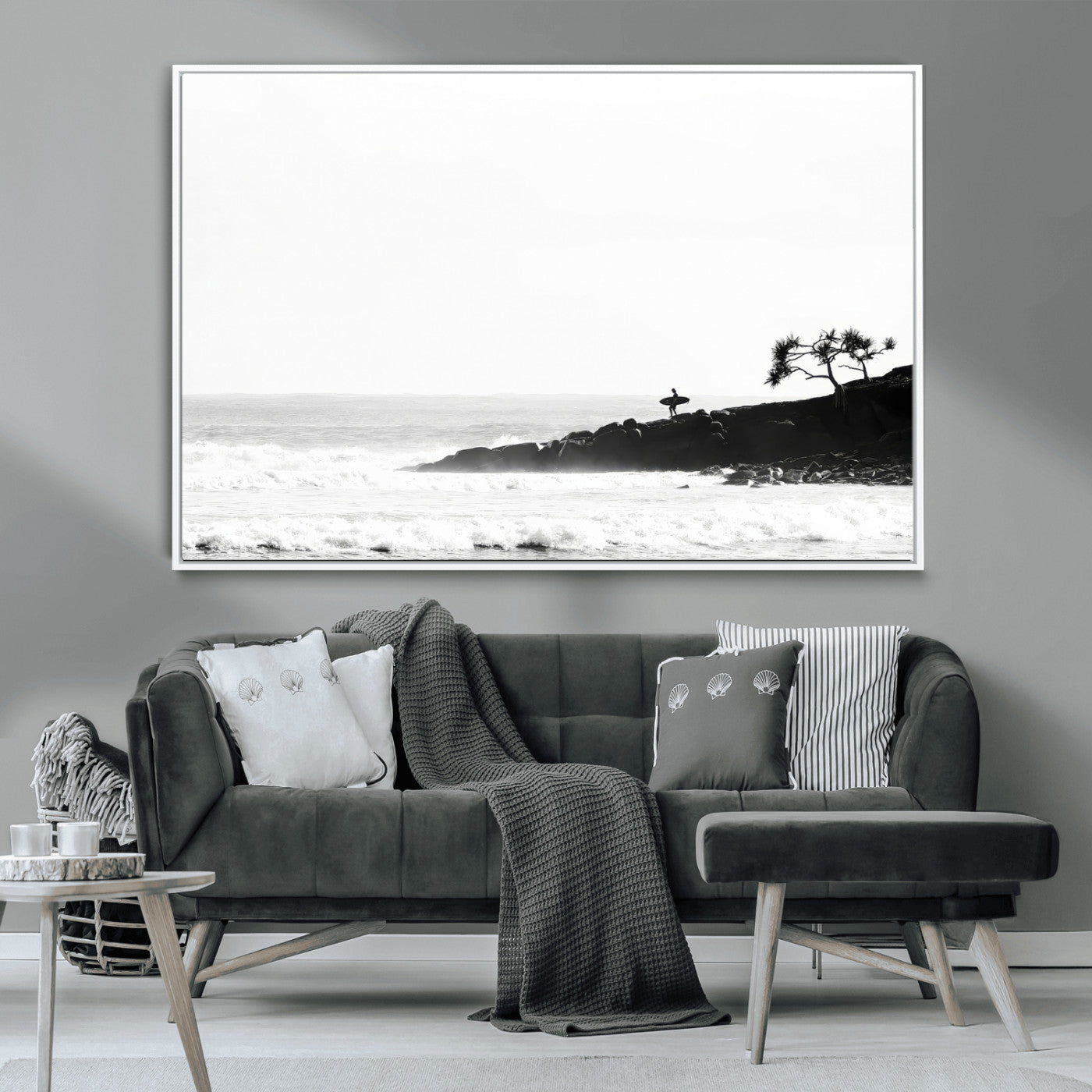 Black and white photo of a surfer standing on rocky cliffs, gazing at the waves, embodying the spirit of adventure and solitude.