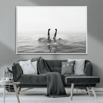 A black and white minimalist water scene capturing a playful splash as a swimmer dives upside down, creating a carefree and artistic aquatic aesthetic.