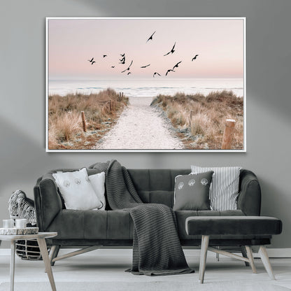 A peaceful coastal pathway leading to the ocean, with birds flying across a soft pastel sky, creating a calm and scenic beach atmosphere.