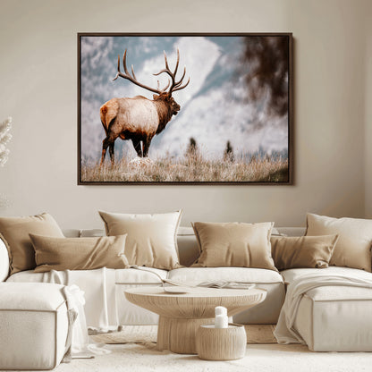 Majestic elk with large antlers standing in grass with snowy mountains in background, perfect for rustic cabin or lodge style decor.