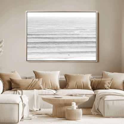 Monochrome photo of a lone surfer in calm layered waves, perfect for minimalist coastal or moody ocean-inspired wall decoration.