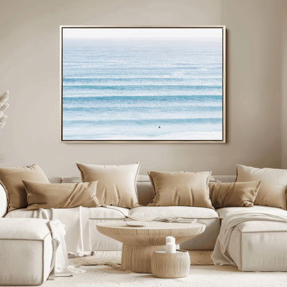 Minimalist ocean view with soft blue waves and a lone surfer, creating a serene and airy coastal aesthetic, perfect for tranquil home decor.