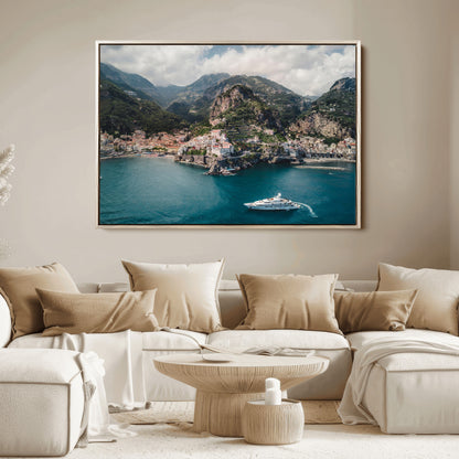 Aerial view of Amalfi Coast, Italy, with colorful hillside houses, lush green mountains, and a luxury yacht sailing in turquoise waters.