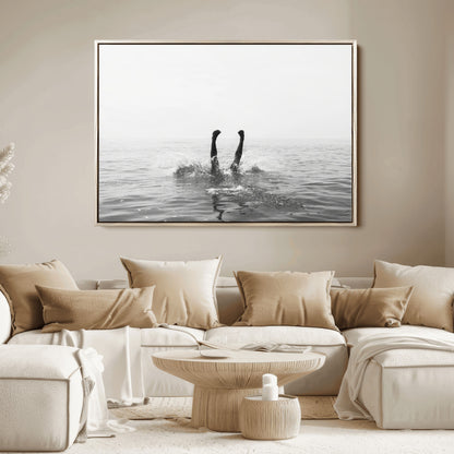 A black and white minimalist water scene capturing a playful splash as a swimmer dives upside down, creating a carefree and artistic aquatic aesthetic.