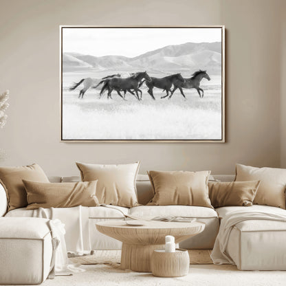 A black and white image of wild horses running freely across an open grassland, capturing the power and beauty of untamed nature in a rustic western setting.