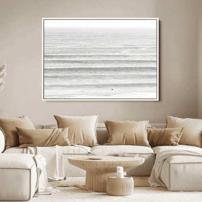 Monochrome photo of a lone surfer in calm layered waves, perfect for minimalist coastal or moody ocean-inspired wall decoration.