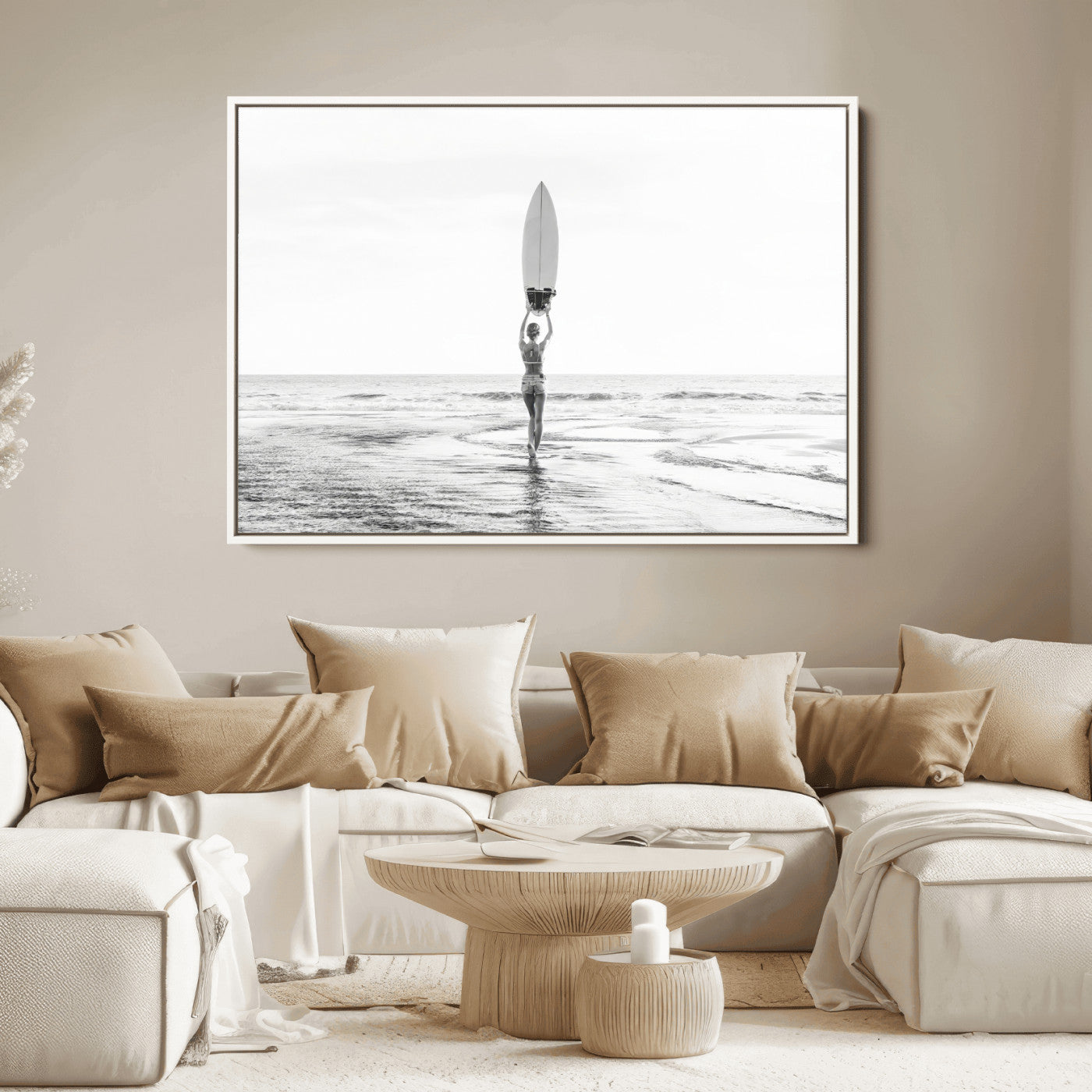 Black and white image of a female surfer holding a surfboard above her head while walking toward the ocean, creating a minimalist and bold coastal aesthetic.
