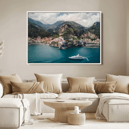 Aerial view of Amalfi Coast, Italy, with colorful hillside houses, lush green mountains, and a luxury yacht sailing in turquoise waters.