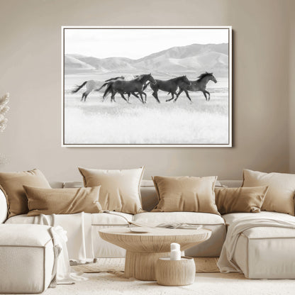 A black and white image of wild horses running freely across an open grassland, capturing the power and beauty of untamed nature in a rustic western setting.