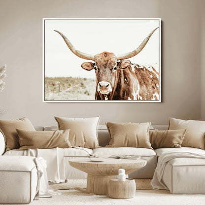 A Texas longhorn bull with wide horns, standing in a dry field under soft light, ideal for rustic farmhouse or western-themed interiors.