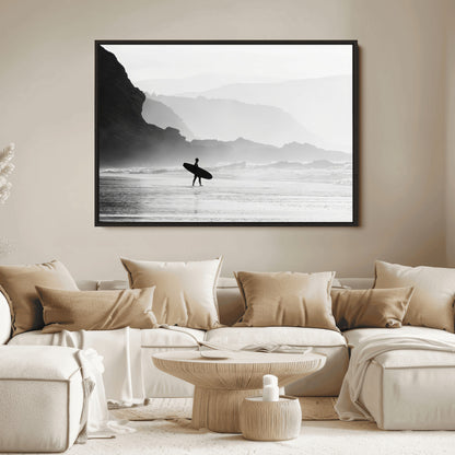 A lone surfer walking along a misty beach with cliffs in the background, carrying their board, capturing a serene and minimal ocean moment.