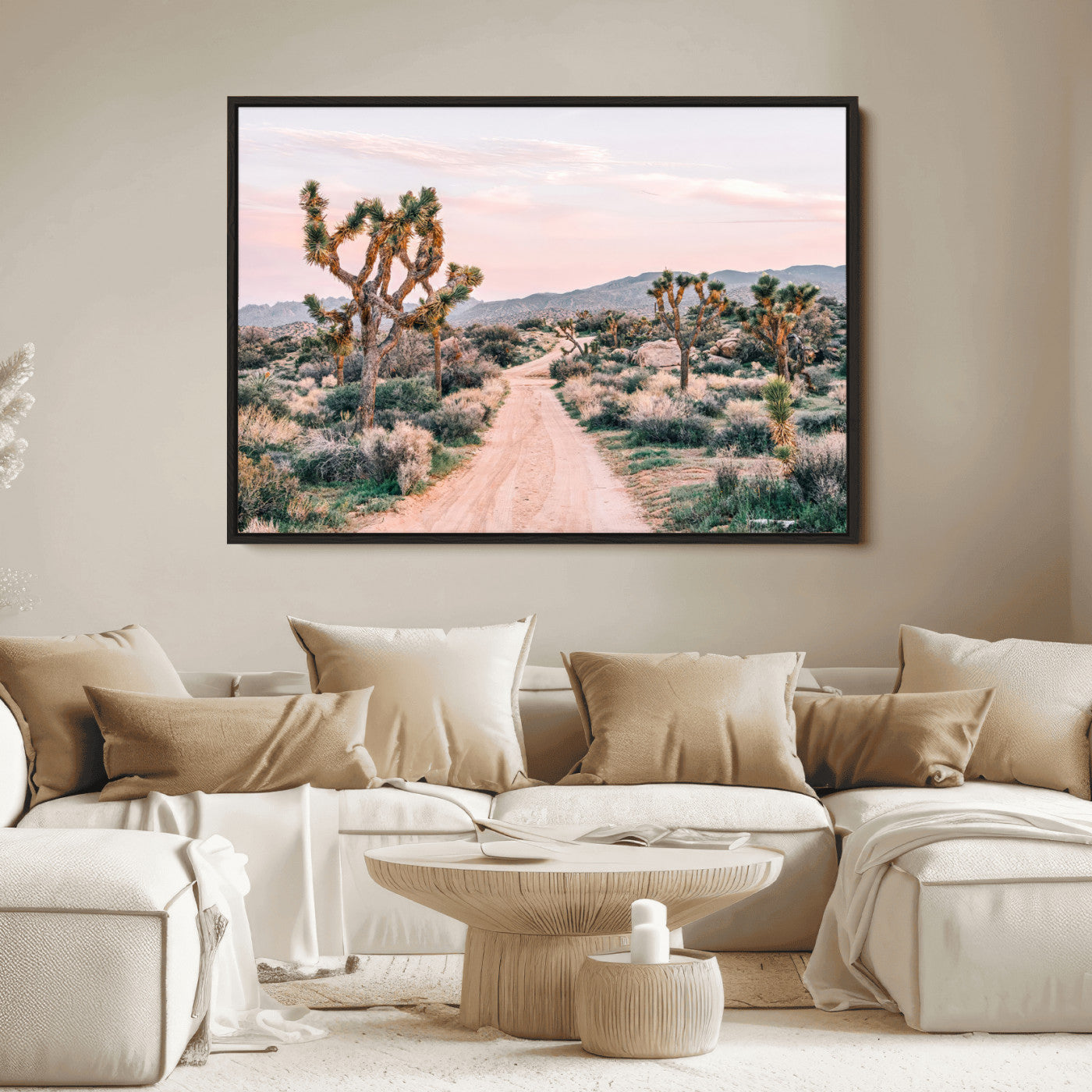 A dusty road winding through Joshua Tree National Park, framed by iconic twisted trees and warm desert tones under a soft pastel sky.