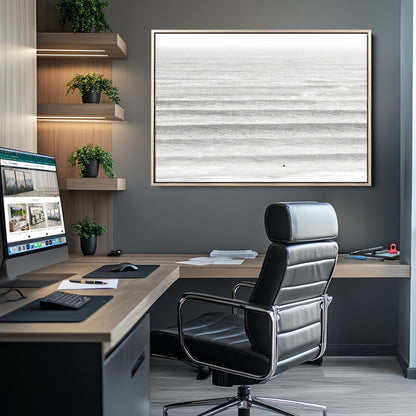 Monochrome photo of a lone surfer in calm layered waves, perfect for minimalist coastal or moody ocean-inspired wall decoration.