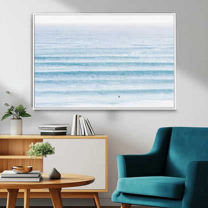Minimalist ocean view with soft blue waves and a lone surfer, creating a serene and airy coastal aesthetic, perfect for tranquil home decor.