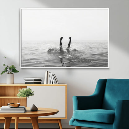 A black and white minimalist water scene capturing a playful splash as a swimmer dives upside down, creating a carefree and artistic aquatic aesthetic.