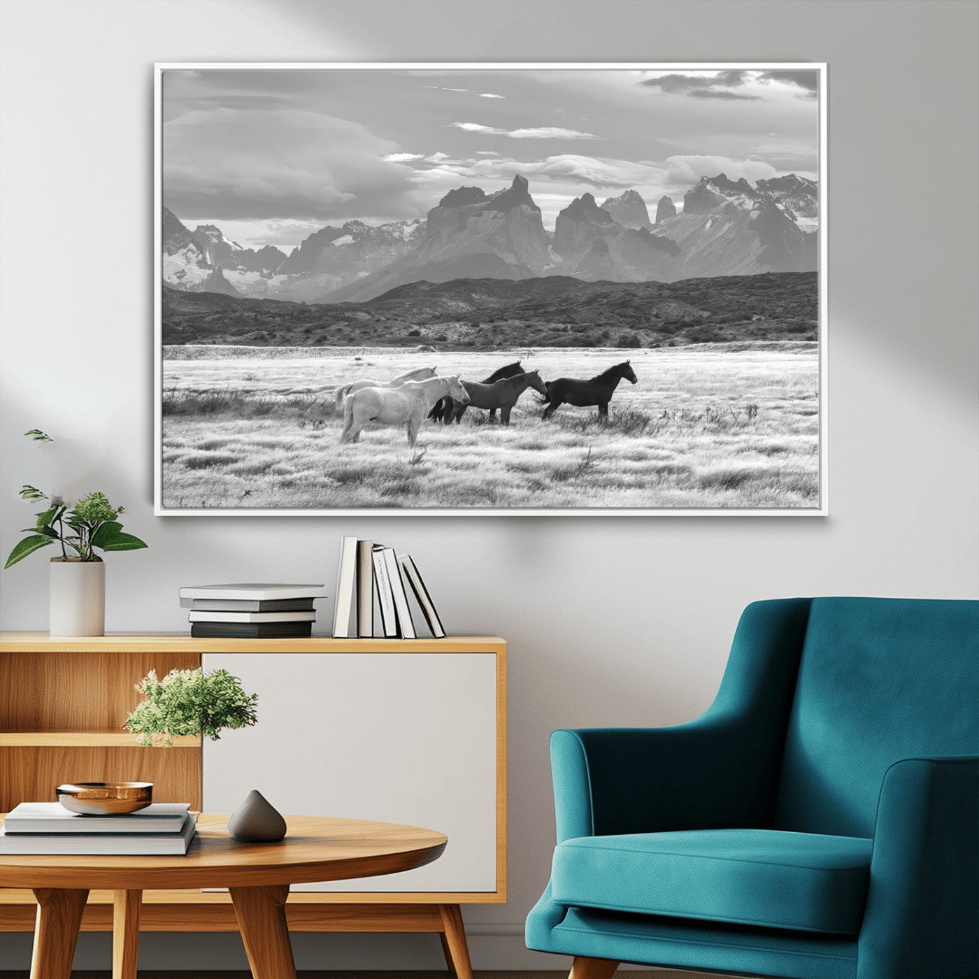 A black and white landscape of wild horses grazing in a vast grassland with towering mountains in the background, creating a moody and rustic western aesthetic.